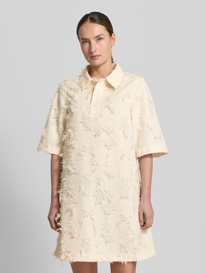 Frauenmodel trägt Minikleid mit kurzer Knopfleiste Modell 'Mialle' von mbyM in Creme, Strukturmuster, Gerader-Schnitt, Polokragen, Nahaufnahme Oberkörper. Rückenlänge 89 cm, Brustweite 34 cm, Ärmellänge 36 cm bei Größe S.