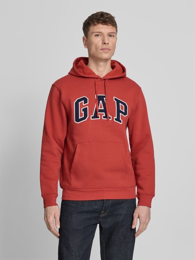 Männermodel trägt Hoodie mit Kängurutasche von GAP in Rot, Baumwoll-Mix, lockere passform, Kapuze mit Tunnelzug, Nahaufnahme Oberkörper.