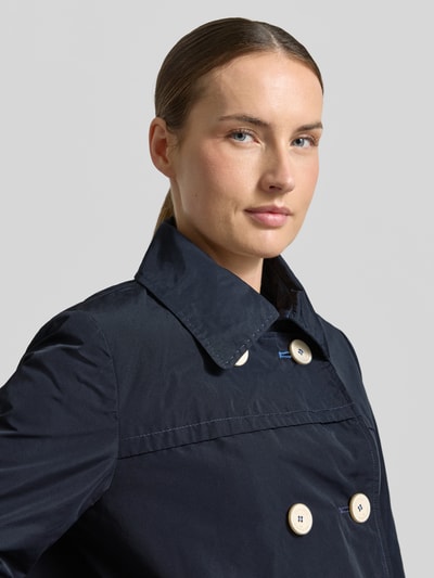 Frauenmodel trägt Jacke mit Ärmelriegeln von Amber & June in Dunkelblau, sichtbarer Zweireiher, Umlegekragen, Nahaufnahme Oberkörper.