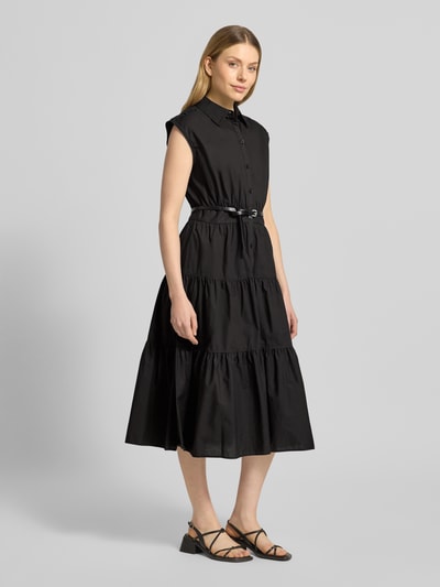 Frauenmodel trägt Hemdblusenkleid mit Gürtel und Knopfleiste von MICHAEL Michael Kors in Schwarz, reine Baumwolle, tailliert, Midilänge, Volantsaum, ganzkörperansicht von vorne.