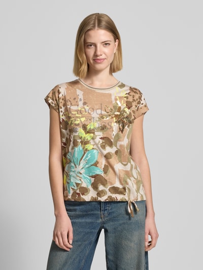 Frauenmodel trägt T-Shirt im Allover-Look mit Ziersteinbesatz von Betty Barclay, Baumwoll-Modal-Mix, Regular-Fit, Rundhalsausschnitt, Tunnelzug, Rückenlänge bei Größe 36: 57 cm, florale Muster in Beige und Blau, glatte und leicht glänzende Textur, Ganzkörperansicht von vorne.