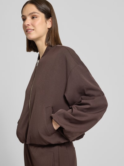 Kobiece model prezentuje Jacke mit Reißverschluss Modell 'Janica' od OPUS w kolorze ciemnobrązowym, krój regular fit, miks materiałów z wiskozą, stójka, zamek, półdługa długość, szerokość w rozmiarze 36: 65 cm, całkowity widok z przodu.