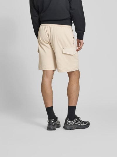 Männermodel trägt Shorts mit elastischem Bund von Moose Knuckles in Beige mit Cargo-Taschen, Straight Fit, Rückansicht Ganzkörperansicht.