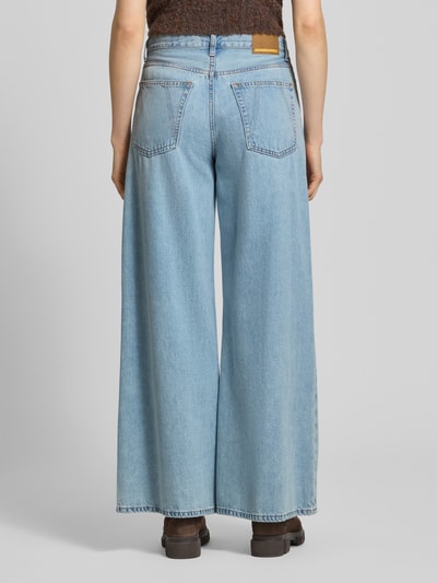 Modelka nosi Loose Fit Jeans aus Baumwoll-Lyocell-Mix Modell 'ASTRAEAAS' od Armedangels, jasny denim, szerokie nogawki, naszywka z logo, szlufki na pasek, 5 kieszeni, zapięcie na guzik i zamek błyskawiczny, mieszanka bawełny i lyocellu, widok całej sylwetki od tyłu.