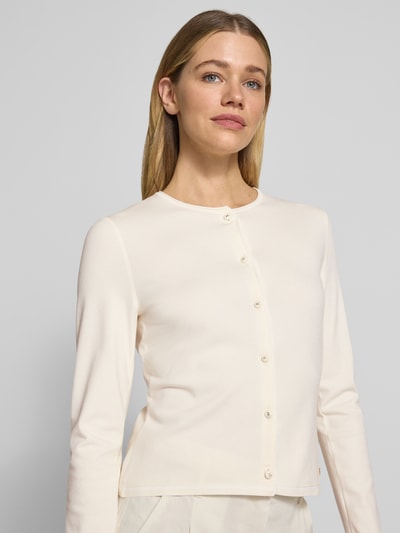 Frauenmodel trägt Cardigan aus Viskose-Mix mit Kontrastkante von Marc Cain, cremefarben, gerader Schnitt, Knopfleiste, Nahaufnahme Oberkörper.