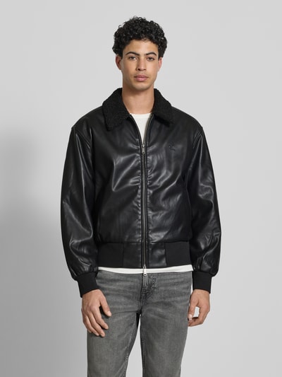 Männermodel trägt Regular Fit Jacke in Leder-Optik mit Umlegekragen von Calvin Klein Jeans, Schwarz, Zweiwege-Reißverschluss, Vorderansicht, Ganzkörperansicht von vorne.