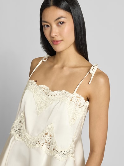Frauenmodel trägt Regular Fit Top mit Spitzenbesatz Modell 'Kaela' von Neo Noir, elfenbeinfarben, Satin, elastisch, Nahaufnahme Oberkörper.