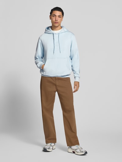 Männermodel trägt Hoodie aus Baumwoll-Mix Modell 'FREDERIKS' von JACK & JONES in Hellblau, lockere Passform, Ganzkörperansicht von vorne.