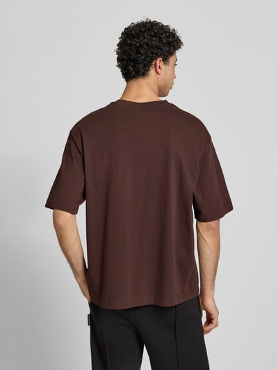 Männermodel trägt T-shirt mit ronde hals van PUMA PERFORMANCE in bruin, relaxed fit, puur katoen, logoprint, ruglengte maat M 69 cm, Ganzkörperansicht Rückansicht.