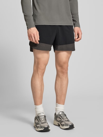 Männermodel trägt schwarze Regular-Fit Herren Shorts mit elastischem Bund und Reißverschlusstaschen, Modell 'HALO DIVISION' von HALO, Ganzkörperansicht von vorne. Bundweite bei Größe M: 40 cm, Innenbeinlänge 10 cm.
