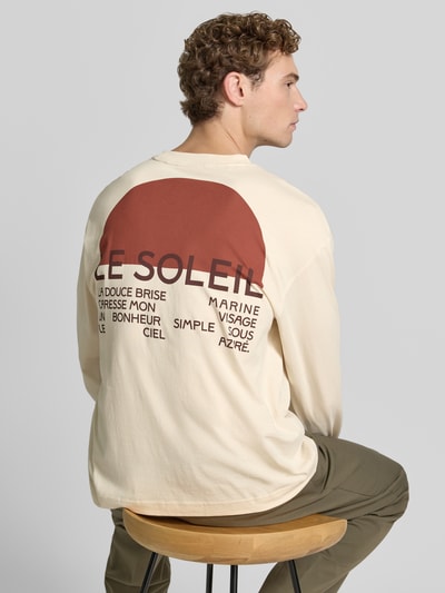Männermodel trägt Relaxed Fit T-Shirt aus reiner Baumwolle Modell 'AXMAX' von Selected Homme in Beige mit großem Print, Herren T-Shirt, Ganzkörperansicht Rückansicht.
