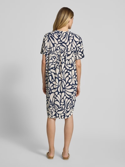 Frauenmodel trägt knielanges Kleid mit V-Ausschnitt Modell 'Floy' von FREE/QUENT, Muster in Dunkelblau und Creme, Ganzkörperansicht Rückansicht.