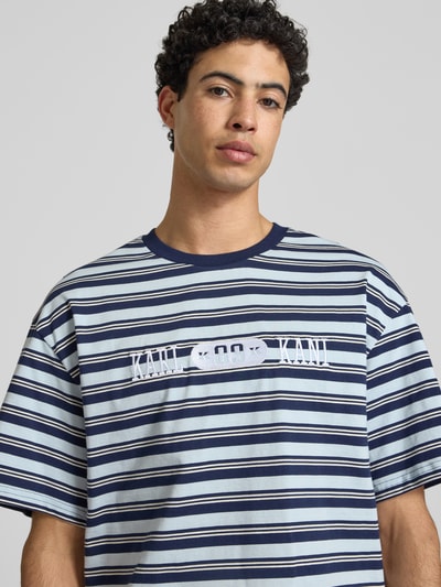 Männermodel trägt Regular Fit T-Shirt mit Logo-Stitching von KARL KANI, gestreift in Blau und Weiß, Reine Baumwolle, Nahaufnahme Oberkörper.