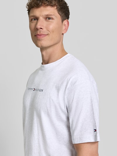 Männermodel trägt Regular Fit T-Shirt aus reiner Baumwolle von Tommy Hilfiger in Weiß, unifarben, Label Print, Rundhals, Jersey, Nahaufnahme Oberkörper.