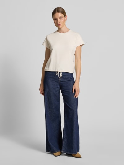 Vrouwenmodel draagt Regular Fit T-shirt uit viscose-mix model 'Solke' van OPUS in licht beige met structuurpatroon, tunnelkoord aan zoom, frontale full-body weergave.