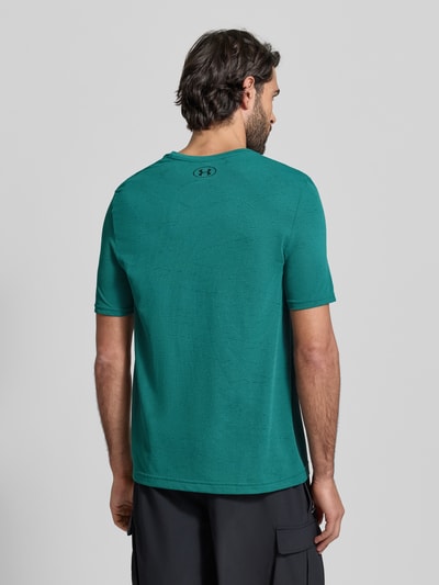 Männermodel trägt Slim Fit T-Shirt mit Logo-Print Modell 'Vanish' von Under Armour, Lochmuster, grün, Ganzkörperansicht Rückansicht.