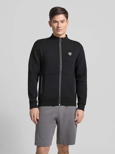 Männermodel trägt schwarze Sweatjacke mit Reißverschluss von EA7 Armani, Regular-Fit, Stehkragen, Eingrifftaschen, Label-Detail, Ganzkörperansicht von vorne.