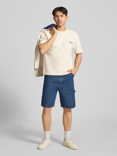 Männermodel trägt T-Shirt mit Label-Stitching von REVIEW in Creme mit Waffelstruktur, Baumwoll-Mix, Gerader-Schnitt, Rundhalsausschnitt, Rückenlänge 68 cm, Ganzkörperansicht von vorne.