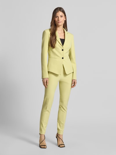 Vrouwenmodel draagt Slim Fit Kurzblazer met Logo-Applikation Modell 'Agonia-1' van HUGO, effen lichtgeel, reverskraag, lange mouw, twill, met paspelzakken en 2-knoopsluiting, detailafwerking, vooraanzicht volledige lichaamsopname.