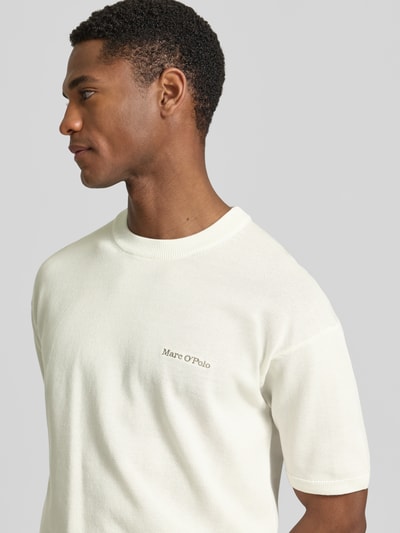 Männermodel trägt Regular Fit T-Shirt aus reiner Baumwolle Marc O'Polo × DFB Travel Collection, Optik: Unifarben, Label-Stitching-Applikation, Rundhals, Kurzarm, Materialverarbeitung: Strick, Nahaufnahme Oberkörper.
