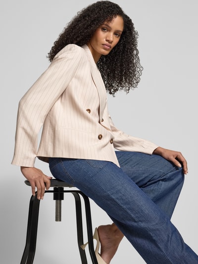 Frauenmodel trägt Regular Fit Blazer mit Reverskragen von Jake*s Collection in Beige mit feinen Streifen, Zweireiher, Paspeltaschen, kombiniert mit blauer Hose, Nahaufnahme Oberkörper, seitliche Perspektive. Rückenlänge bei Größe 38: 59 cm, Brustweite: 49 cm, Ärmellänge: 63 cm.