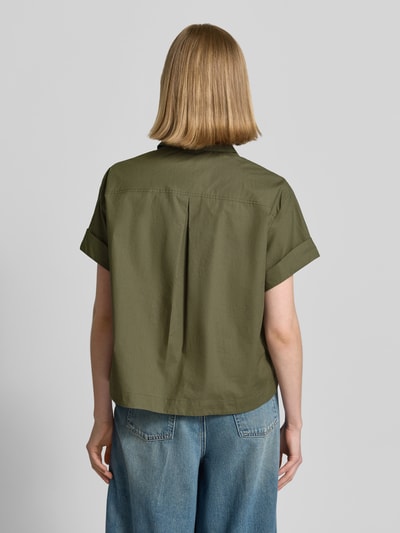 Frauenmodel trägt Boxy Fit Bluse mit Brusttasche von Luisa Cerano aus reiner Baumwolle in Olivgrün, kurze Ärmel, Rückenlänge 57 cm, Ärmel mit Aufschlag, Ganzkörperansicht Rückansicht.