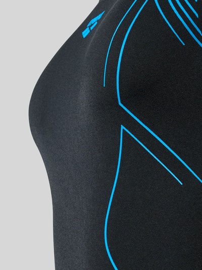 Frauenmodel trägt Slim Fit Badeanzug mit Logo-Print von Arena in Schwarz mit blauen Linien, strukturierte Textur, Nahaufnahme Oberkörper.