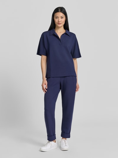 Modelka damska nosi Regular Fit Poloshirt mit V-Ausschnitt von Christian Berg Woman, mieszanka materiałów z domieszką modalu, dekolt w serek, rękaw o dł. 1/2, kolor granatowy, gładka tekstura, widok całej sylwetki z przodu.
