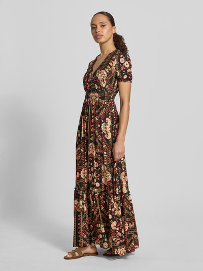 Frauenmodel trägt Maxikleid aus Viskose mit V-Ausschnitt von Apricot, Taillierter Schnitt, Smok-Detail, Rüschenärmel, Volantsaum, Rückenlänge 138 cm, Brustweite 44 cm, Ärmellänge 20 cm, florales Muster in warmen Farbtönen, Ganzkörperansicht von vorne.