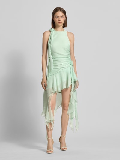 Frauenmodel trägt Cocktailkleid mit asymmetrischem Rock Modell 'IVANA' von Bardot aus Chiffon, Minikleid mit floralen Applikationen und Raffungen, sanft grüne Töne, Ganzkörperansicht von vorne.