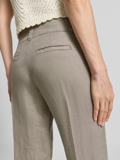 Kobieta nosi Leinenhose mit Eingrifftaschen od Christian Berg Woman, czysta len, krój regular fit, beżowy, tekstura lnu, zbliżenie na tylne kieszenie, detal tył.
