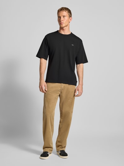 Männermodel trägt T-Shirt mit Label-Print von Levi's®, schwarze Farbe, lockerer-Schnitt, reine Baumwolle, Rundhalsausschnitt, Ganzkörperansicht von vorne.