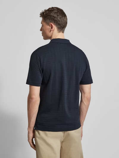 Männermodel trägt Regular Fit Poloshirt aus reiner Baumwolle von Marc O'Polo, dunkelblau, Gitterkaro Struktur, Ganzkörperansicht Rückansicht.
