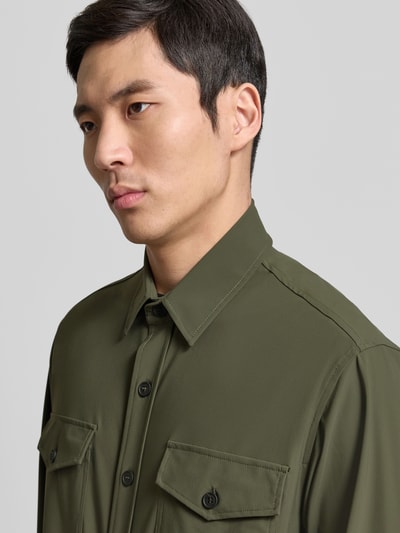 Männermodel trägt olivgrüne Hemdjacke mit Knopfleiste von CRUNA, Regular Fit, Kentkragen, Brusttaschen, Nahaufnahme Oberkörper.