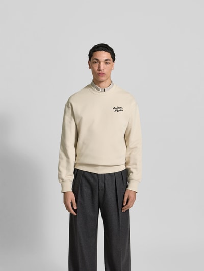 Männermodel trägt Sweatshirt aus Baumwoll-Mix von MAISON KITSUNÉ in Beige mit Label-Stitching, lockerer Passform, Ganzkörperansicht von vorne.