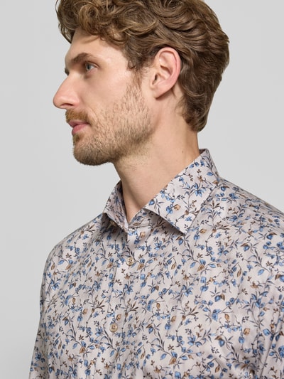 Männermodel trägt Modern Fit Businesshemd aus reiner Baumwolle von OLYMP mit floralem Muster in Beige und Blau, Nahaufnahme Oberkörper, Herren Businesshemd von OLYMP.