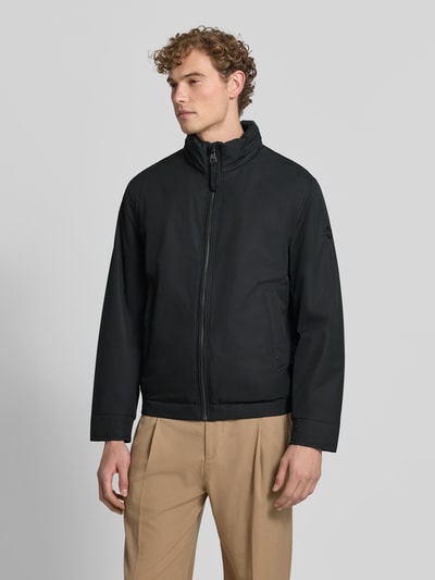 Mężczyzna model nosi Regular Fit Steppjacke mit Stehkragen Modell 'LIGHT' od Strellson, kurtka pikowana w kolorze czarnym, gładka tekstura, Ganzkörperansicht von vorne, kurtka męska Strellson.
