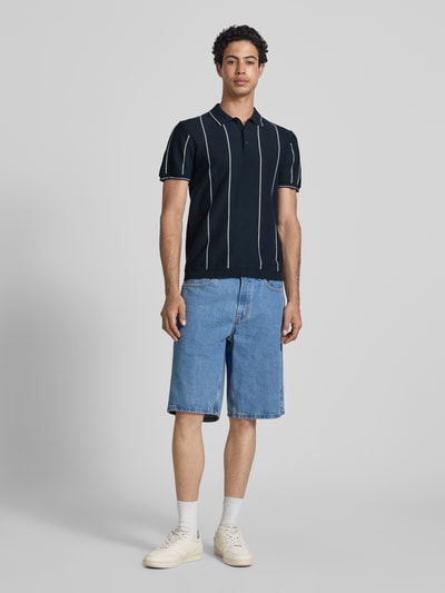 Männermodel trägt Slim Fit Poloshirt mit Knopfleiste Modell 'AVEN' von Blend in Dunkelblau mit weißen Streifen, Baumwolle, Ganzkörperansicht von vorne.