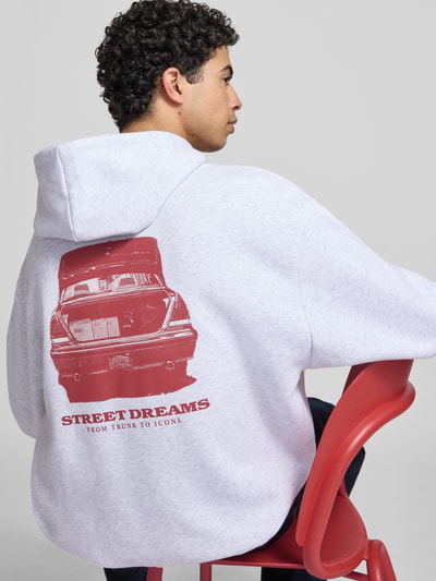Männermodel trägt Oversized Fit Hoodie mit Logo-Stitching von KARL KANI in Hellgrau mit rotem Print, Baumwoll-Mix, Rückenlänge 60 cm, Nahaufnahme Rückansicht.