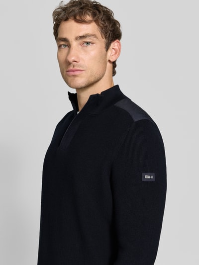 Männermodel trägt gebreide pullover met schoudervullingen van bugatti in donkerblauw, puur katoen, recht model, schipperskraag, ribboorden, ruglengte maat M 68 cm, mouwlengte maat M 70 cm, detailaufnahme bovenlichaam.