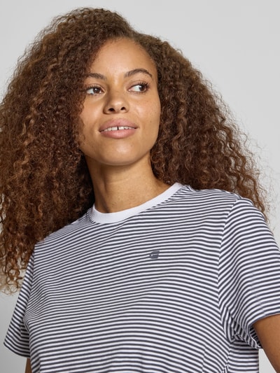 Frauenmodel trägt Relaxed Fit T-Shirt aus reiner Baumwolle mit geknotetem Saum von G-Star RAW, feine schwarz-weiße Streifen, Nahaufnahme Oberkörper.