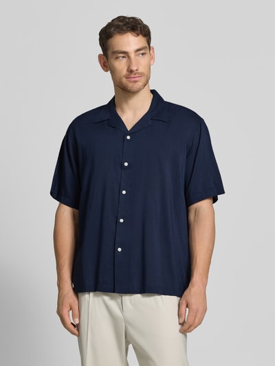 Männermodel trägt Relaxed Fit Freizeithemd aus Bio-Baumwoll-Modal-Mix Modell 'RELAXAIR' von SELECTED HOMME, Optik: Unifarben, Reverskragen, durchgehende Knopfleiste, Ärmelform: Kurzarm, Materialtextur glatt, Farbe Dunkelblau, Ganzkörperansicht von vorne.