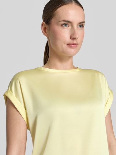 Frauenmodel trägt T-Shirt mit Rundhalsausschnitt Modell 'ELLETTE' von Vila, gelb, lockerer Schnitt, glatte Viskose-Elasthan-Oberfläche, Nahaufnahme Oberkörper.