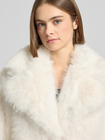 Frauenmodel trägt Mantel aus Kunstfell mit Reverskragen von Gina Tricot in Creme, weiche Textur, Nahaufnahme Oberkörper. Regular Fit, Kunstfell, Rückenlänge 82 cm, Schulterbreite 49 cm, Brustweite 56 cm, Ärmellänge 55 cm.