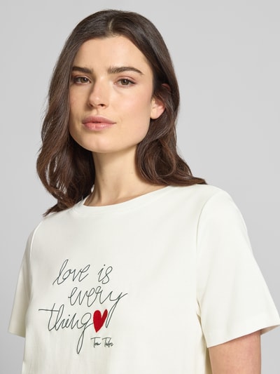 Kobiece modelka nosi Relaxed Fit T-Shirt aus reiner Baumwolle von Tom Tailor w kolorze jednolitym z okrągłym dekoltem, krótki rękaw, motyw nadruku z przodu, materiał czysta bawełna, zbliżenie na górną część ciała.