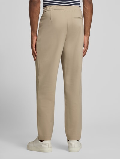 Männermodel trägt Hose mit französischen Eingrifftaschen von CK Calvin Klein in Beige, Tapered Fit, Baumwoll-Mix, Ganzkörperansicht Rückansicht
