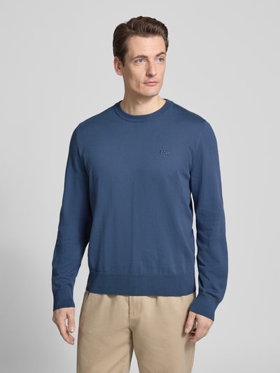 Männermodel trägt Regular Fit Strickpullover aus reiner Baumwolle Modell 'UPCAS' von BOSS in Unifarben mit Label-Stitching, Ganzkörperansicht von vorne.