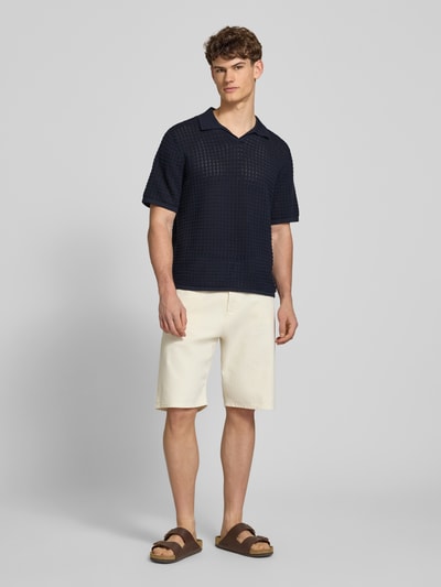 Männermodel trägt Regular Fit Poloshirt mit V-Ausschnitt von Jack & Jones aus reiner Baumwolle, Strickshirt, dunkle Farbe, Ganzkörperansicht von vorne. Rückenlänge bei Größe M: 67 cm.