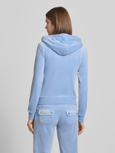 Frauenmodel trägt Slim Fit Sweatjacke aus Samt Modell 'Robertson' von Juicy Couture in Hellblau mit Kapuze, Elastischer-Material-Mix und geteilte Känguru-Tasche, Rückansicht Ganzkörperansicht.