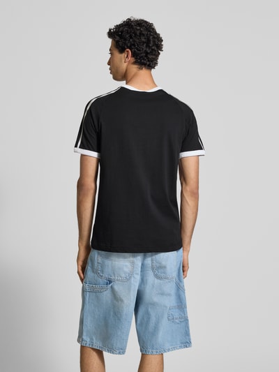 Männermodel trägt Regular Fit T-Shirt mit Logo-Print von PUMA PERFORMANCE in Schwarz mit weißen Details, reine Baumwolle, Ganzkörperansicht Rückansicht.